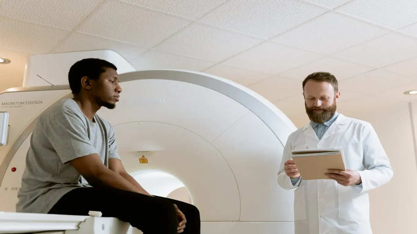 A radiologist reads a patient's charts to him.